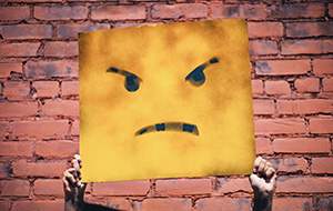 angry face emoji painted on a sign